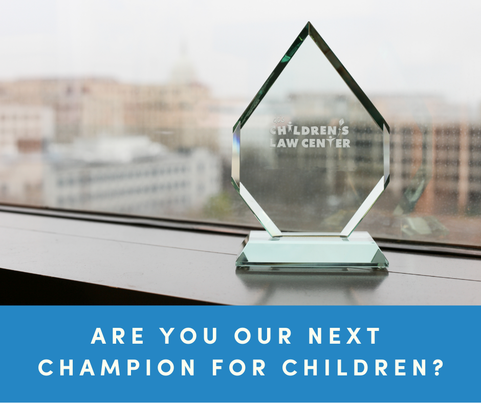 Glass award with Children's Law Center logo on a windowsill. Banner says "Are you our next Champion for Children?"