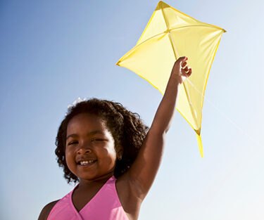 Child holding up a yellow kite