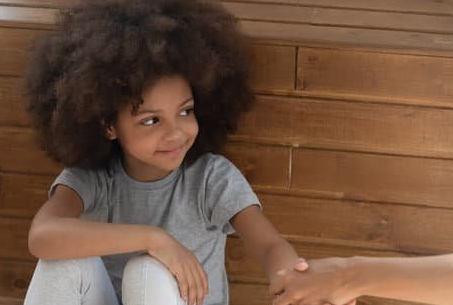 Child holds hands with someone out of the frame.