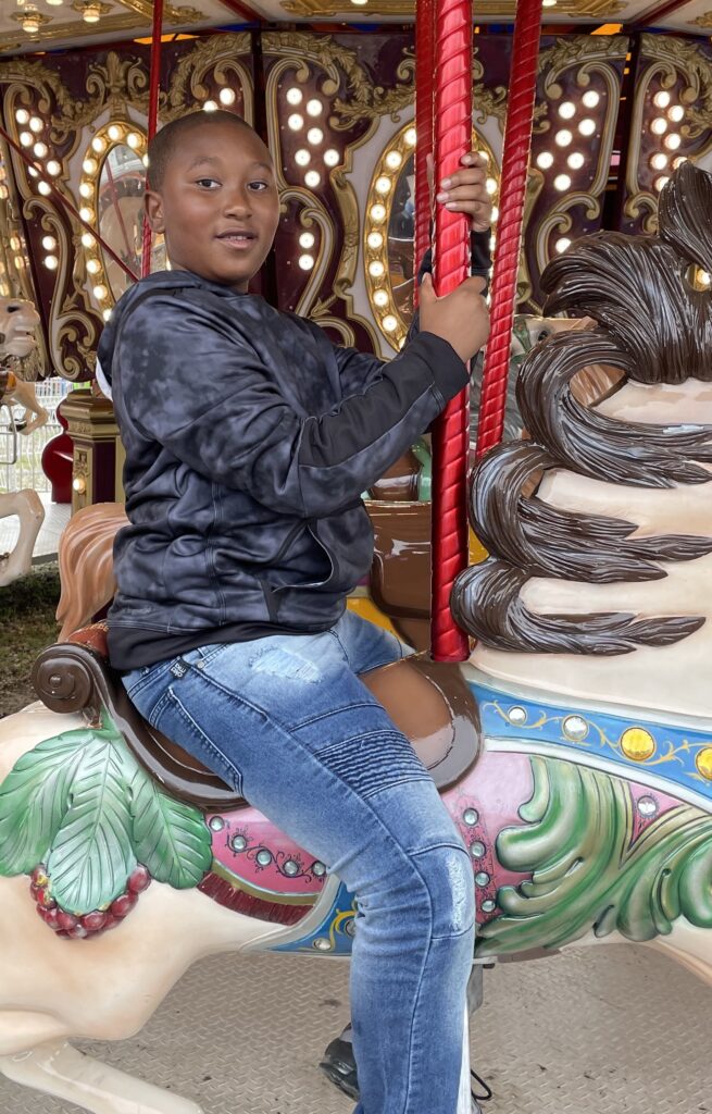 Boy smiling on merry-go-round horse.