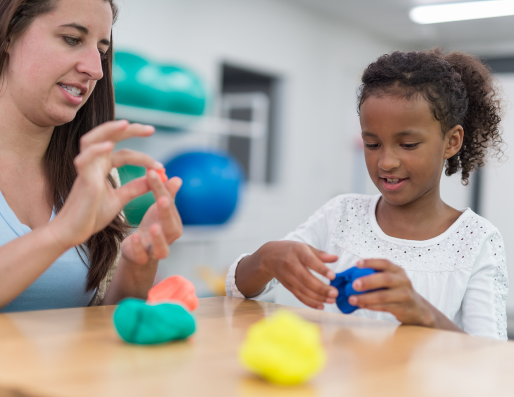 Photo of child with therapist, playing with modeling clay