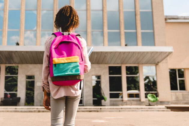 Girl with backpack looking at school.