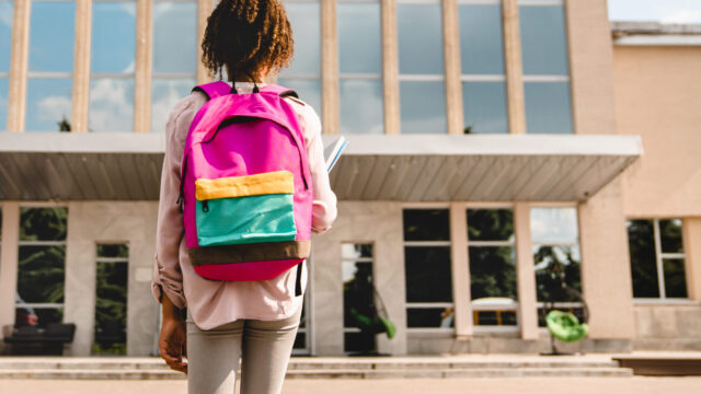 Girl with backpack looking at school building