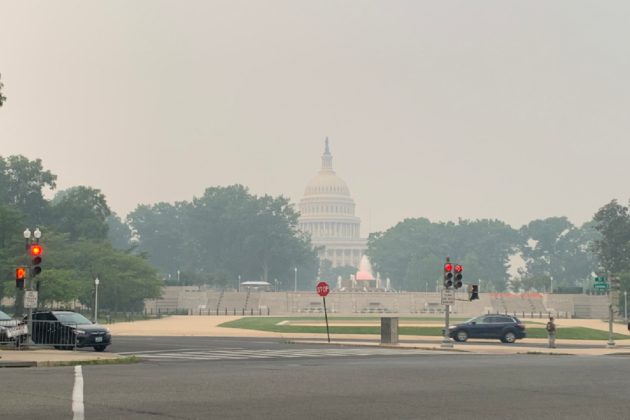Photo of U.S. Capitol Building in the distance with hazy skies.