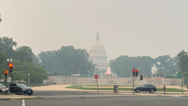Photo of U.S. Capitol Building in the distance with hazy skies.