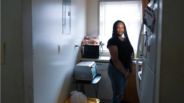 Andrea Dicks stands in the kitchen of her apartment.