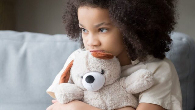 Stock photo of young girl hugging teddy bear