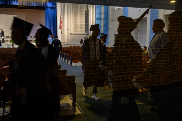 Seniors from Phelps High School are reflected in a window before graduation ceremonies at Eastern High School in 2019. (Michael Robinson Chavez/The Washington Post).