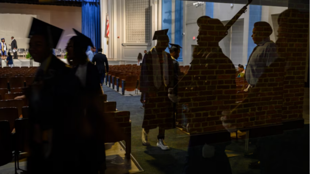 Seniors from Phelps High School are reflected in a window before graduation ceremonies at Eastern High School in 2019. (Michael Robinson Chavez/The Washington Post)