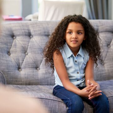 Young girl sitting on couch speaking with therapist