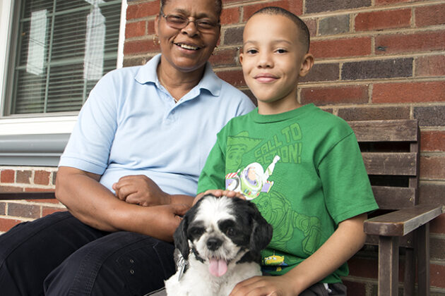 Phyllis and her son, Jordan, sitting on their porch with a small dog.