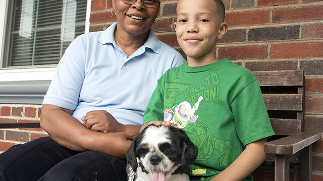 Phyllis and her son, Jordan, sitting on their porch with a small dog.