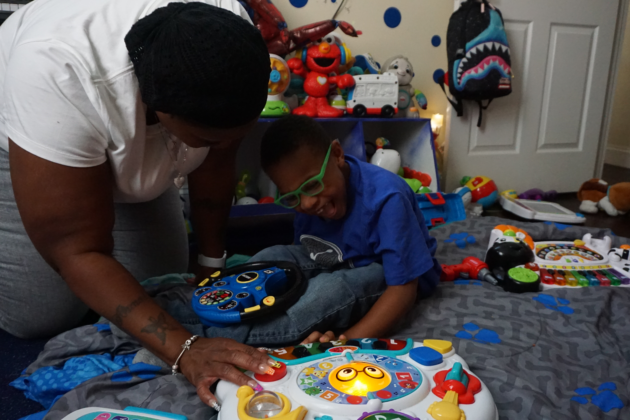 Photo of Ms. Chance playing with her son, Ayden, on the floor of his new bedroom.