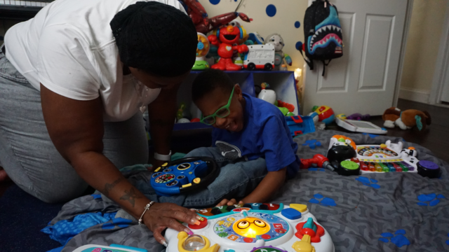 Photo of Ms. Chance playing with her son, Ayden, on the floor of his new bedroom.