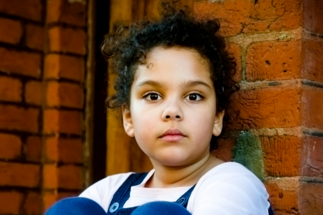 Child sitting outside looking at camera.