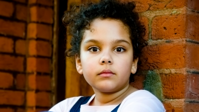 Child sitting outside looking at camera